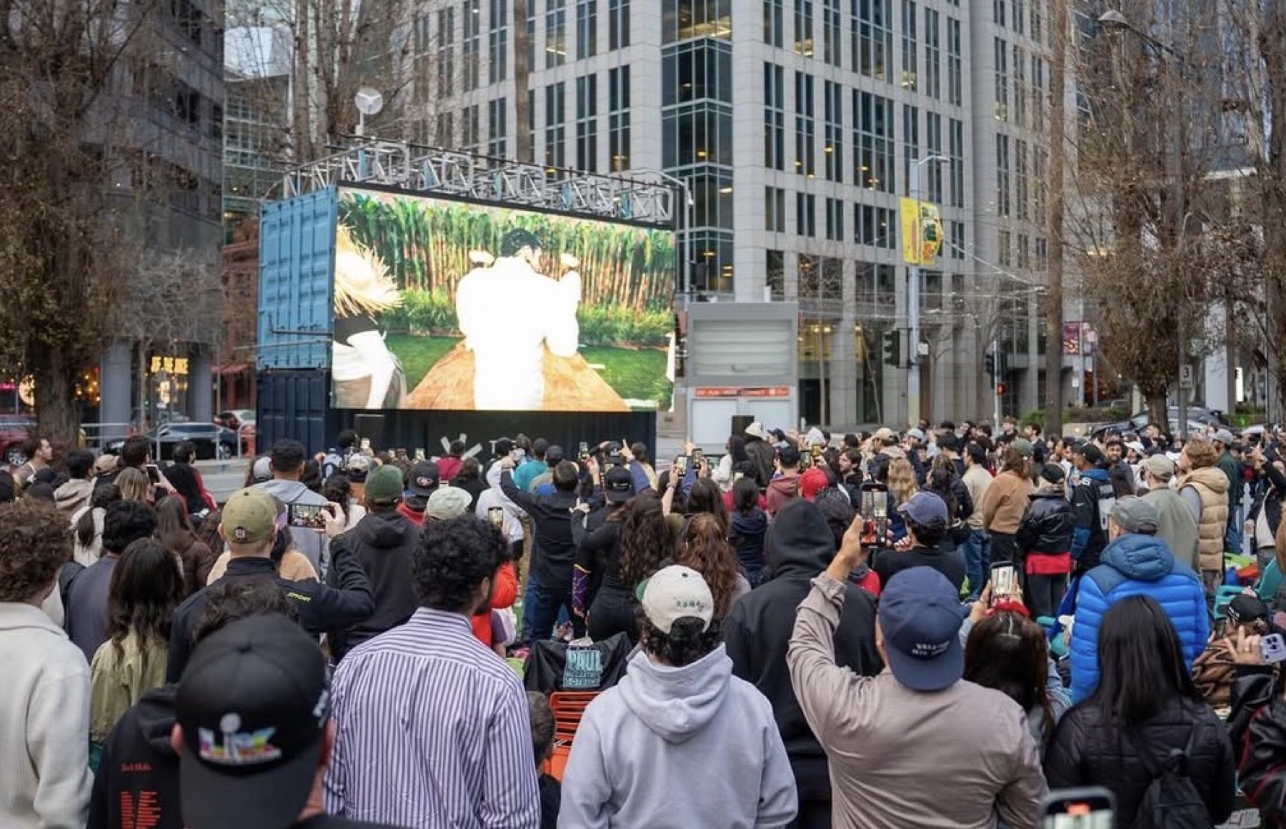 Outdoor crowd watching match on big screen